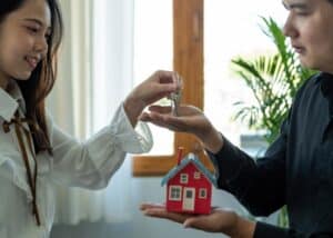picture of a woman handling a key to a man with a miniature house